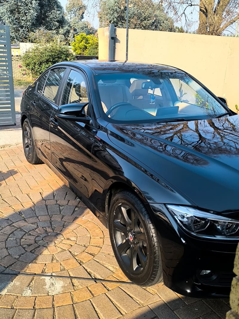Black BMW 3 Series from the side after a full detail, gloss carrying along the flank and wheels cleaned