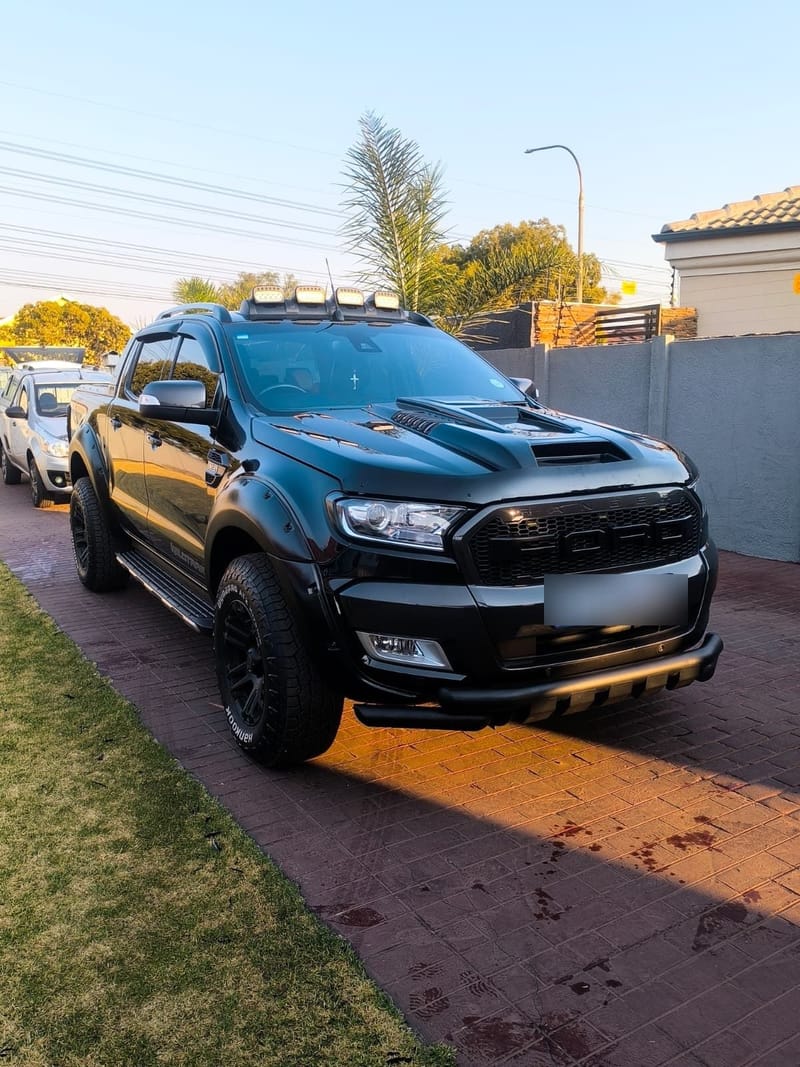 Black Ford Ranger detailed in late afternoon light, paint and wheels cleaned on a driveway